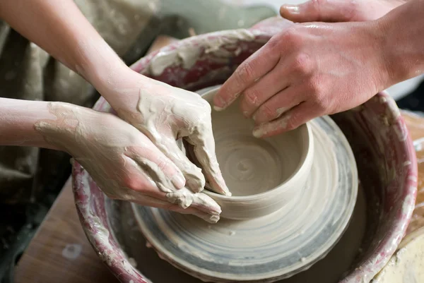 A potters hands guiding pupil hands to help him to work — Stock Photo, Image