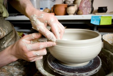 Bir çömlekçinin elleri, çemberin üzerinde toprak kavanozu yaratıyor.