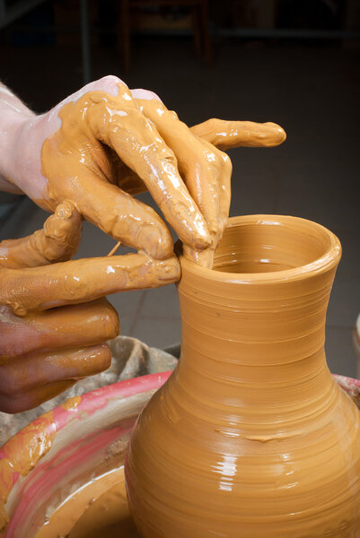 hands of a potter, creating an earthen jar on the circle