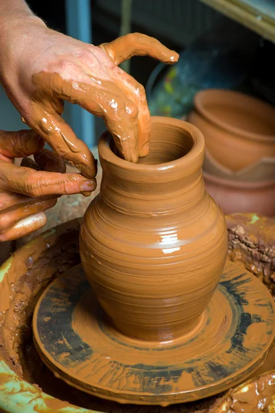 Hands of a potter, creating an earthen jar on the circle — Stock Photo, Image