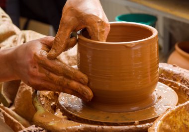 Bir çömlekçinin elleri, çemberin üzerinde toprak kavanozu yaratıyor.