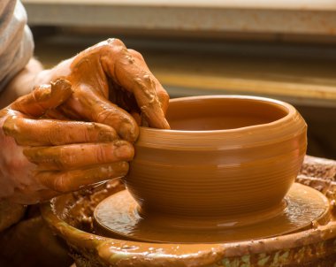 Bir çömlekçinin elleri, çemberin üzerinde toprak kavanozu yaratıyor.