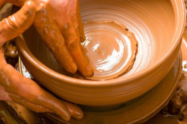 Bir çömlekçinin elleri, çemberin üzerinde toprak kavanozu yaratıyor.