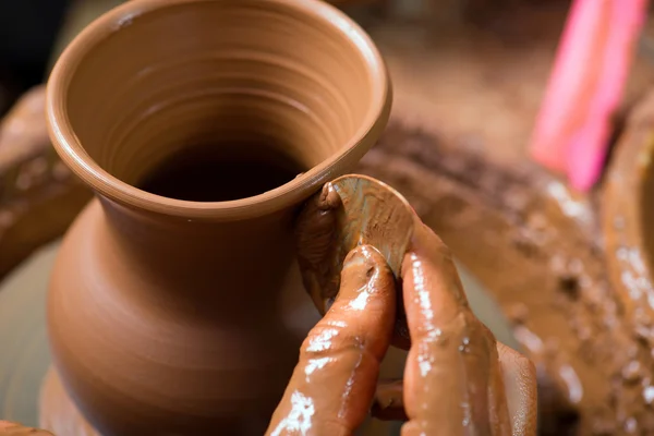 Hands of a potter, creating an earthen jar on the circle — Stock Photo, Image