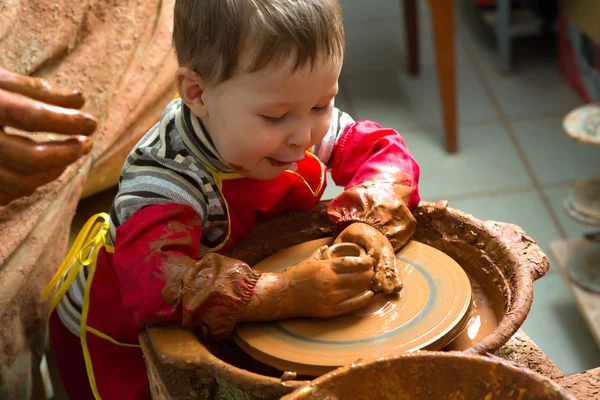 A potters hands guiding pupil hands to help him to work with the ceramic wheel — Stock Photo, Image