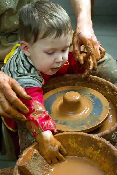 Een pottenbakkers handen leidende leerling handen om te helpen hem om te werken met de keramische wheel — Stockfoto