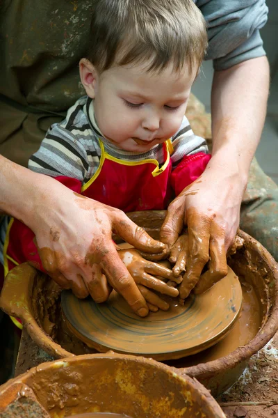 A potters hands guiding pupil hands to help him to work with the ceramic wheel — Stock Photo, Image