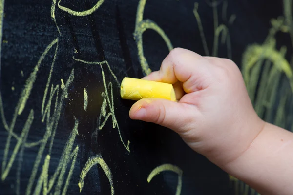 Child draws with chalk on a blackboard — Stock Photo, Image