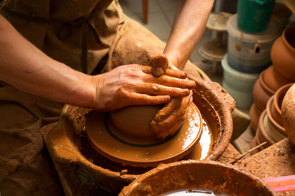 hands of a potter, creating an earthen jar