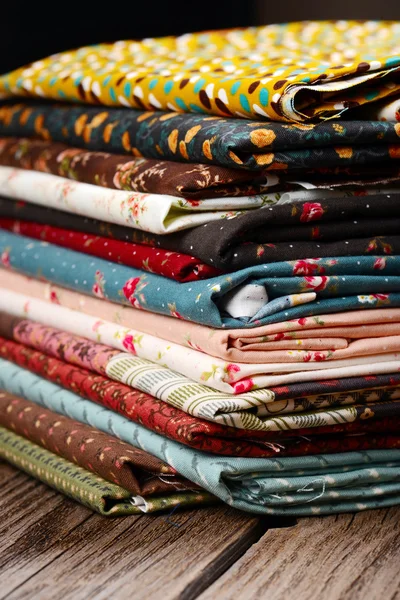 Heap of cloth fabrics on wooden table — Stock Photo, Image