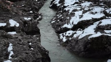 Gün batımında karlı dağ nehri. Yeşil renkli su.