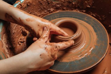 Potter atölyede çember tekerleği üzerinde çalışıyor.