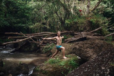 Yoga uygulaması ve doğada meditasyon. Nehir yakınlarında pratik yapan adam