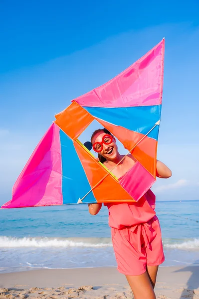 Meisje in jurk met zonnebril op het strand van de zee met kite hebben jo Stockfoto