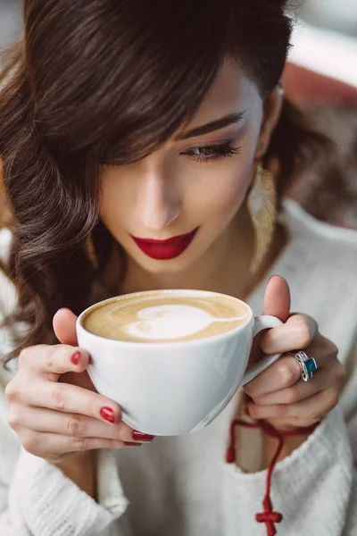 Молодая девушка пьет кофе в модном кафе — стоковое фото