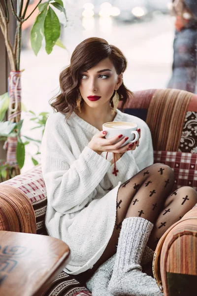Молодая девушка пьет кофе в модном кафе — стоковое фото