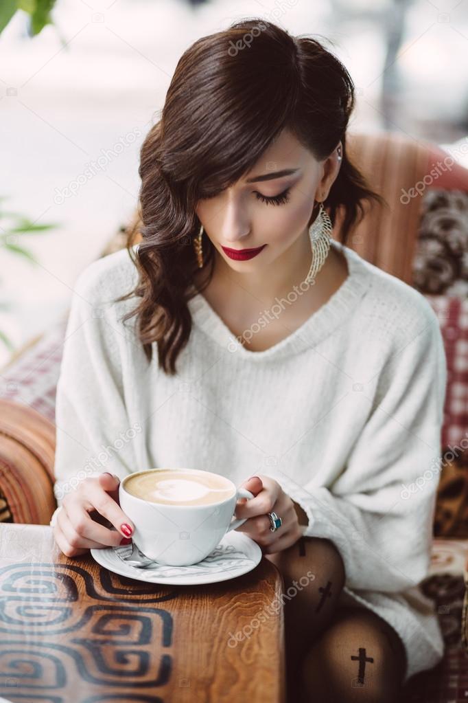 Young girl drinking coffee in a trendy cafe