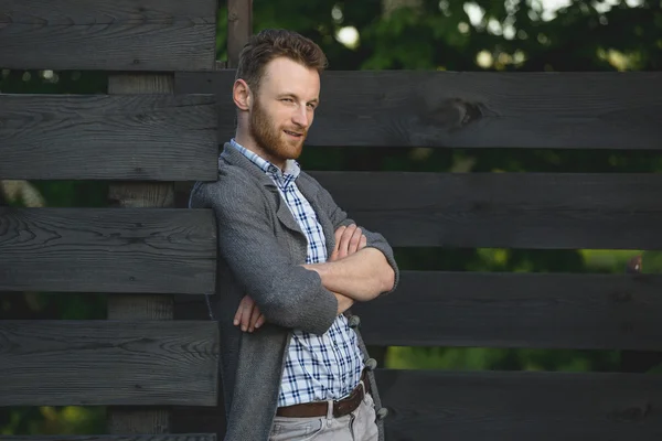 Portret van modieuze jongeman tegen houten hek — Stockfoto