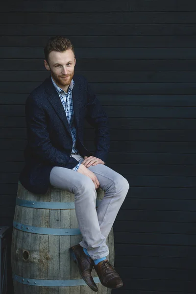 Man in een jasje zittend op een vat — Stockfoto