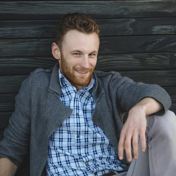 Handsome young man sitting on the wooden floor — Stock Photo, Image