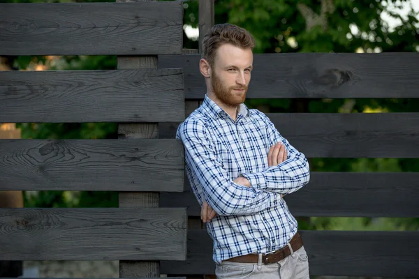 Portrét mladé módní člověka proti dřevěný plot — Stock fotografie
