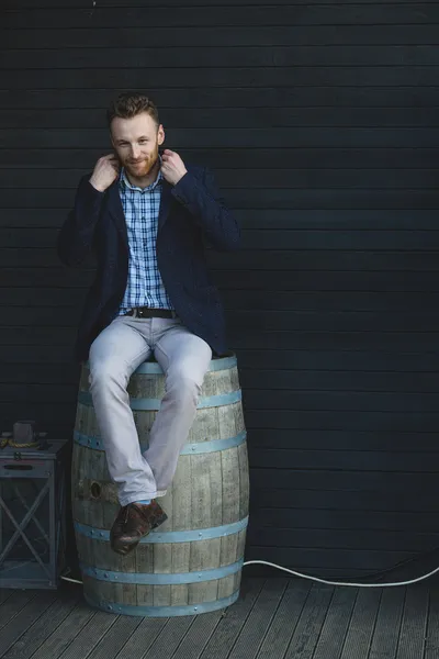 Man in een jasje zittend op een vat — Stockfoto