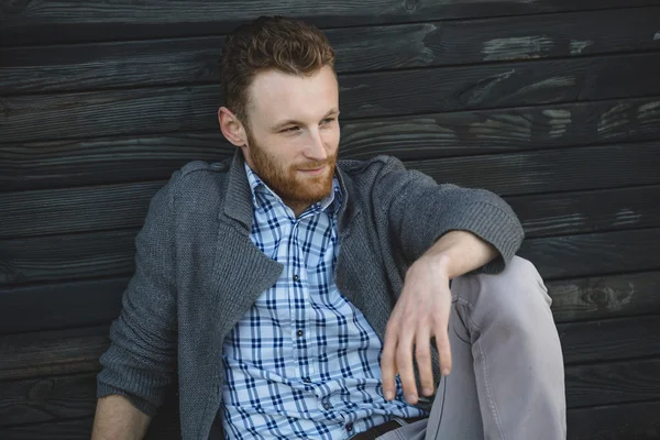 Knappe jonge man zittend op de houten vloer — Stockfoto