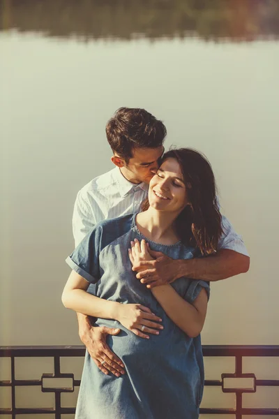 Coppia felice e giovane incinta che si abbraccia nella natura al lago. V — Foto Stock