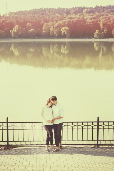 Coppia felice e giovane incinta che si abbraccia nella natura al lago. V — Foto Stock