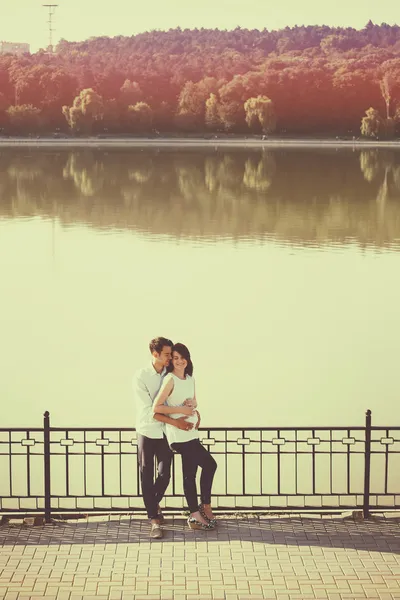 Coppia felice e giovane incinta che si abbraccia nella natura al lago. V — Foto Stock