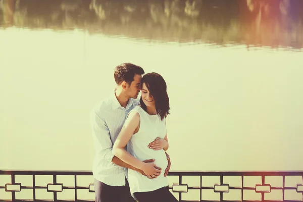 Feliz y joven pareja embarazada abrazándose en la naturaleza en el lago. V. — Foto de Stock