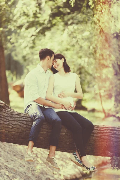 Feliz y joven pareja embarazada abrazándose en la naturaleza. Vintage retro —  Fotos de Stock