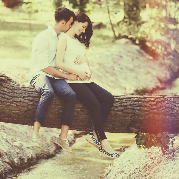 Glückliche und junge schwangere Paare, die sich in der Natur umarmen. Vintage-Retro — Stockfoto