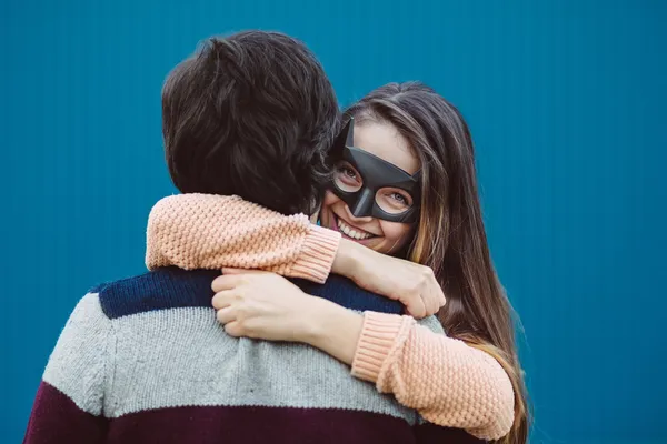 Chica en una máscara besando a su chico joven . — Foto de Stock