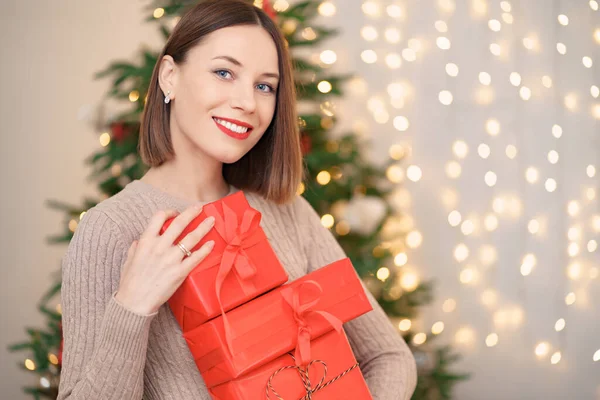 Belle femme brune tenant tas de boîtes-cadeaux dans le salon décoré — Photo