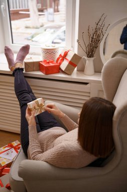 Elinde hediyeyle bir koltukta oturan bir kadın.
