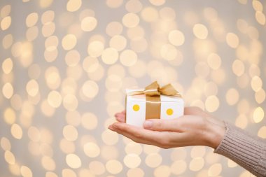 Bir kadın tarafından tutulan sihirli, parıldayan bir hediye kutusu.