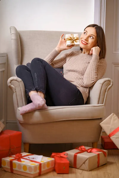 Elinde hediyeyle bir koltukta oturan bir kadın.