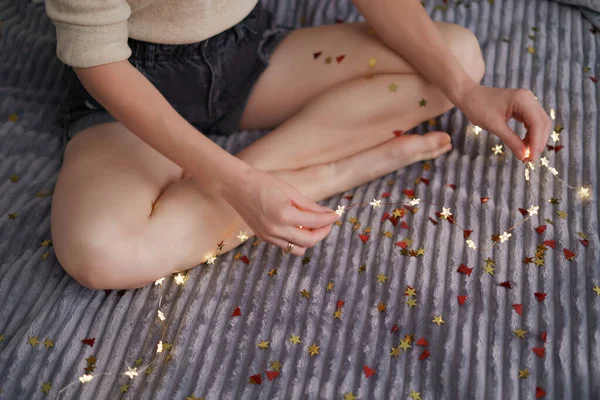 Mulher mãos segurando luzes sentado na cama — Fotografia de Stock