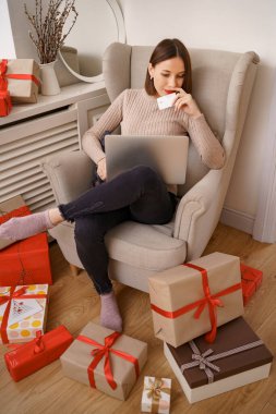 Genç bir kadın kredi kartı ve dizüstü bilgisayarla online alışveriş yapıyor.
