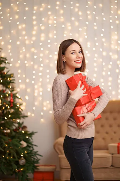 Belle femme brune tenant tas de boîtes-cadeaux dans le salon décoré — Photo