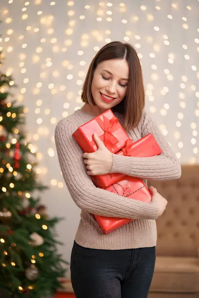 Mulher morena bonita segurando montão de caixas de presente na sala de estar decorada — Fotografia de Stock