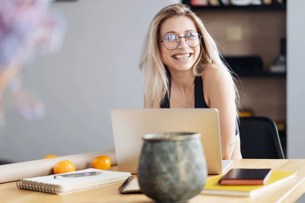 Молода жінка в окулярах сидить за столом дивитися вебінар робить нотатки — стокове фото