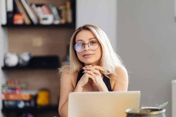 Молода жінка в окулярах сидить за столом дивитися вебінар робить нотатки — стокове фото