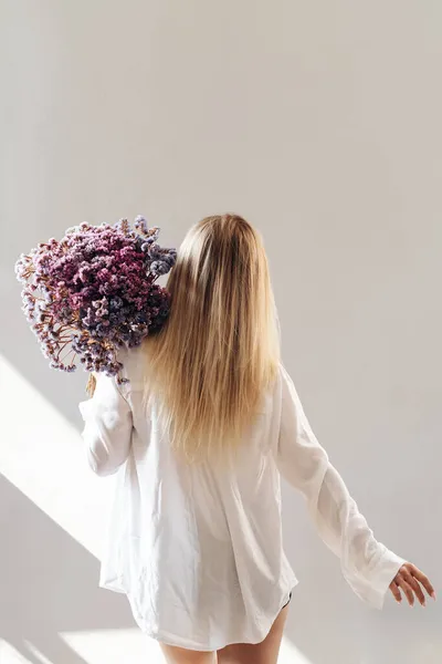 Young woman in white shirt posing with a bunch of flowers — Stock Photo, Image