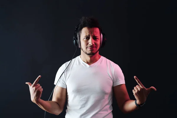 Carefree dark skinned guy portrait wearing headphones on black background — Stock Photo, Image