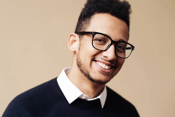 Afro bom cara olhando no preto suéter e óculos posando no bege fundo — Fotografia de Stock