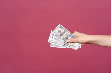 Pembe arka planda para tutan kadın.