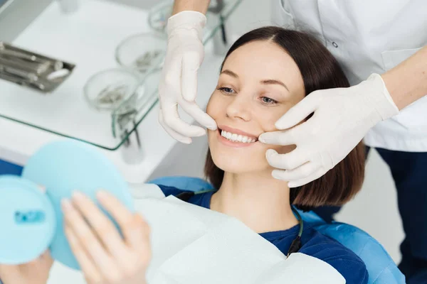 치과 의사들의 손 과 치료 후 거울을 보는 행복 한 환자 — 스톡 사진