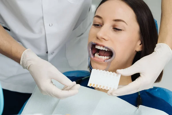 치과의 사는 젊은 여자 치아의 색깔을 검사하고 선택 한다 — 스톡 사진